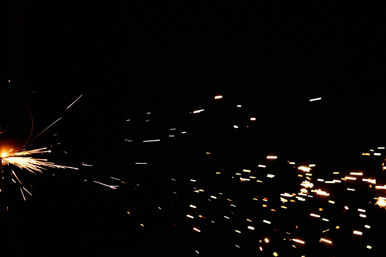 Captivating image of bright metal grinding sparks against a dark background, perfect for industrial themes.
